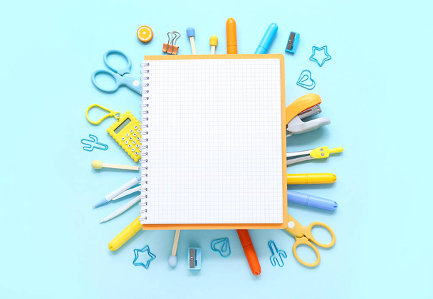 Notebook s různými kancelářskými potřebami na modrém pozadí - Fotografie, Obrázek