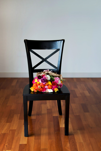 Μάτσο Ranunculus σε μια μαύρη καρέκλα - Φωτογραφία, εικόνα