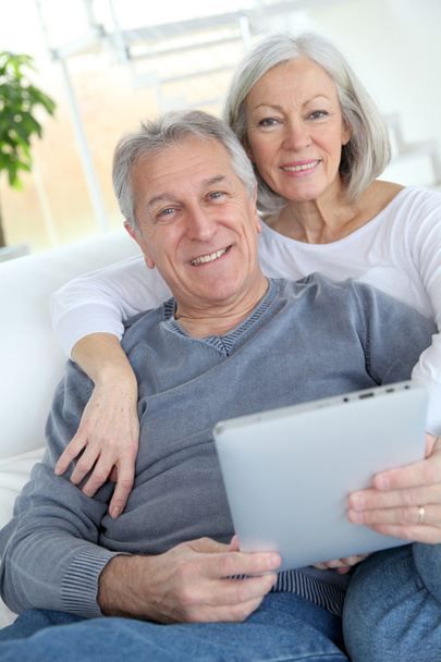 Senior couple sitting in sofa with electronic tablet - Zdjęcie, obraz