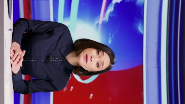 Függőleges videó Ázsiai műsorvezető ad otthont hírek szegmens élő program, címmel minden szalagcímet a hírszobában. Friss híreket és globális eseményeket bemutató női médiaújságíró, televíziós tartalom - Felvétel, videó