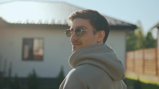 Portrait of a young attractive guy. A man in sunglasses looks at the camera happily and smiles enjoying the rays of the sun. High quality 4k footage - Footage, Video