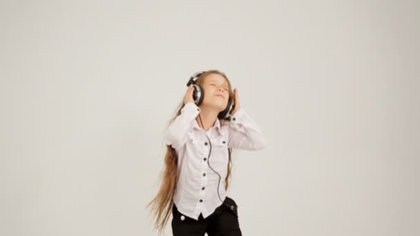 kleines Mädchen, das mit Kopfhörern Musik hört und springt. Zugesperrt. - Filmmaterial, Video