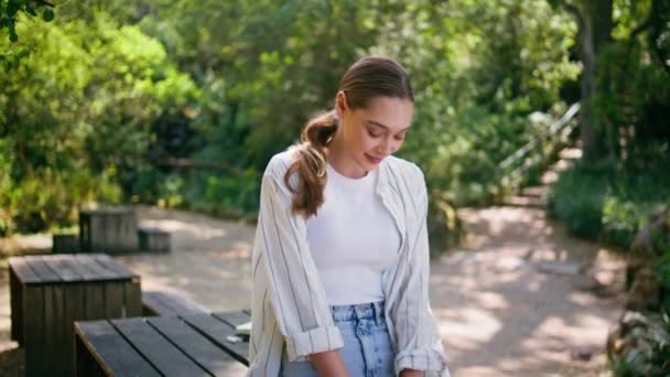 Romantic model posing at summer forest leaning on wooden table. Happy gorgeous woman looking camera with smile relaxing on green nature. Carefree young girl enjoy sunny weekend at woodland recreation. - Footage, Video