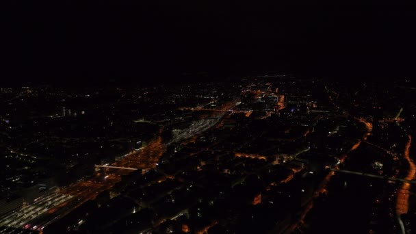 Vista panorâmica aérea da cidade à noite. Ruas iluminadas e infra-estrutura ferroviária contraindo com edifícios escurecidos. Zurique, Suíça. - Filmagem, Vídeo