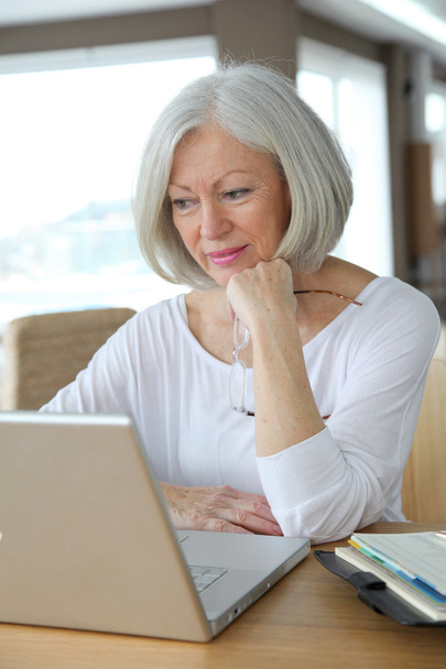 Mujer mayor en casa delante de la computadora portátil
 - Foto, imagen