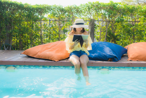Retrato joven asiática mujer leer libro alrededor de piscina al aire libre en hotel resort - Foto, imagen