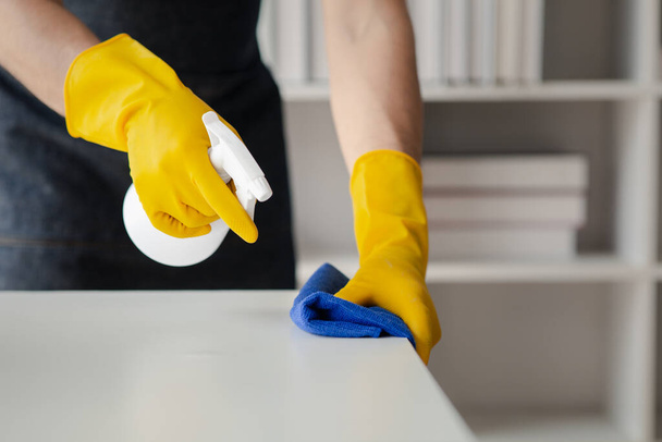Osoba sprzątająca pokój, personel sprzątający używa tkaniny i środka dezynfekującego do wycierania stołów w biurze firmy. Sprzątacze. Utrzymanie czystości w organizacji. - Zdjęcie, obraz