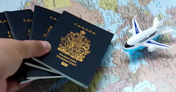Альберта, Канада. 4 серпня 2023 року. Людина, яка скинула канадські паспорти на карту світу з літаком. Концепція: громадяни Канади, які виїжджають за кордон.  - Кадри, відео