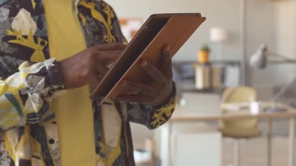 Colpo ritagliato di uomo nero irriconoscibile in camicia colorata stampata utilizzando tablet pc in ufficio - Filmati, video