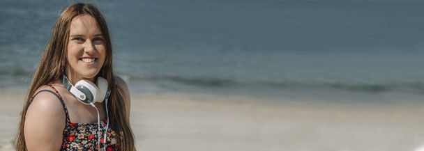 happy young plus size woman with headphones on the beach - Foto, imagen