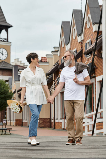 glückliches älteres Paar mit Sonnenbrille, lächelnd und Händchenhaltend, zusammen spazieren, einkaufen, Sommer - Foto, Bild