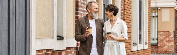 счастливая пожилая пара ходьба с кофе возле здания, пожилой мужчина и женщина, смех, баннер - Фото, изображение