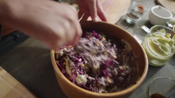 Zblízka vysoký úhel záběr rukou muže míchání červené zelí cole salát s dresinkem v misce při vaření salát v kuchyni stůl - Záběry, video