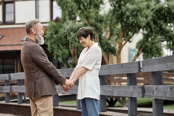 Kadın ve sakallı adam el ele tutuşuyor, birbirlerine bakıyorlar, flört, romantizm, mutlu yaşlı çift. - Fotoğraf, Görsel