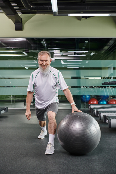 boldog idős sportoló csinál tüdő közelében fitnesz labda, sport és fitness, senior edzés, aktív - Fotó, kép