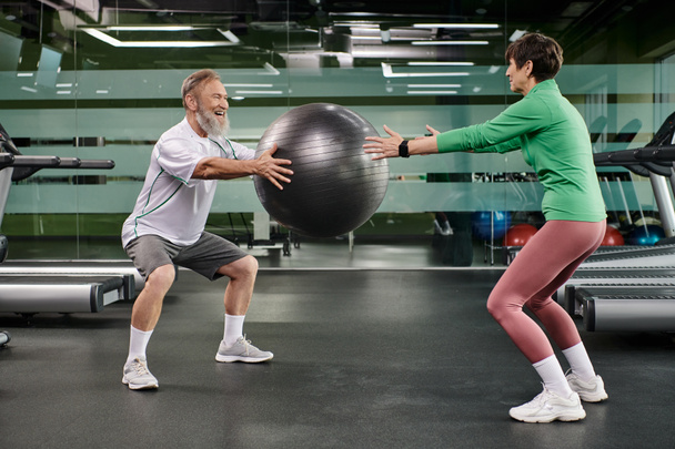 happy elderly man and woman working out with fitness ball in gym, active seniors, couple sport - Photo, Image