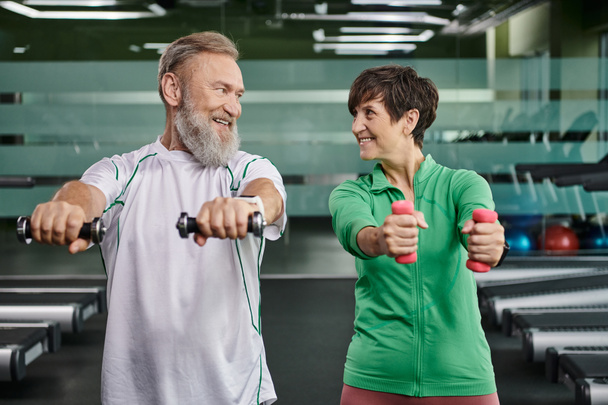 happy elderly couple, happy man and woman training with dumbbells, husband and wife in gym - Photo, Image