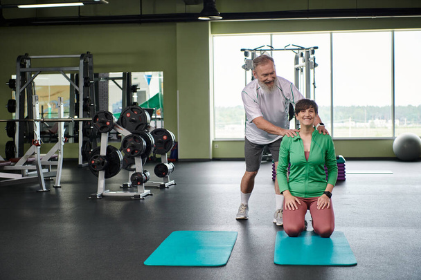 happy elderly man with beard encouraging woman in gym, active, husband and wife, fitness mats - Photo, Image