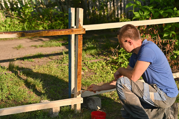 Homme peignant une tache de bois sur une planche de bois - Photo, image