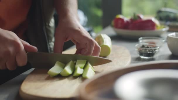 Abgeschnittene Aufnahme der Hände eines Mannes, der frische Zucchini schneidet, während er draußen Essen zubereitet - Filmmaterial, Video