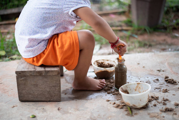 Девочка играет с песком и игрушками на бетонном полу. - Фото, изображение