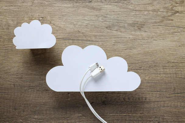 Fehér, papír felhők fehér USB-kábellel, fa alapon - Fotó, kép