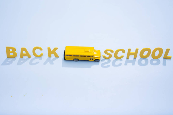 Auf gelbem Grund fährt ein gelber Schulbus mit Fahrbahnmarkierung zurück zur Schule. Konzeptfoto. - Foto, Bild