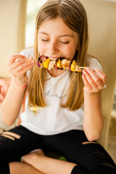 lány eszik csirke nyárson ananásszal otthon - Fotó, kép