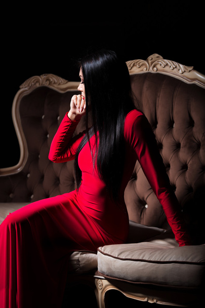 Beautiful lady in red dress on luxury sofa - Zdjęcie, obraz