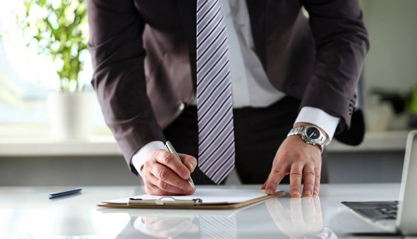 Male arm in suit and tie fill form clipped to pad with silver pen closeup. Sign gesture read pact sale agent bank job make note loan credit mortgage investment finance executive chief legal law - Photo, Image