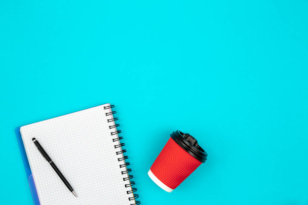 Red paper cup and blank notebook on a blue background, copy space. - Photo, Image
