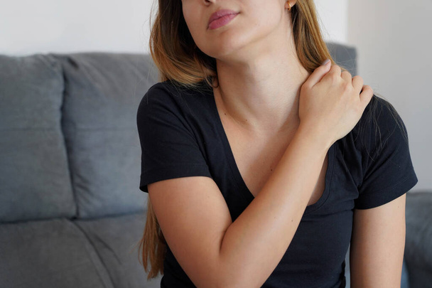 Mujer joven con dolor de hombro. Una chica con un molesto cuello rígido. Concepto Wryneck y dolor postural. - Foto, imagen