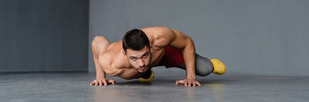 Young shirtless sportsman doing exercise while working out indoors - Foto, immagini