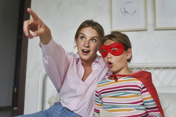 Kaukasische Mutter und Tochter im Superhelden-Outfit zeigen weg - Foto, Bild