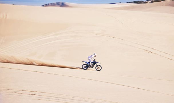 Ποδήλατο, σπορ και ταχύτητα με έναν άντρα στην έρημο για ένα χόμπι γυμναστικής, ελευθερίας ή αδρεναλίνης. Μοτοσικλέτα, εκπαίδευση και καλοκαίρι με έναν άνδρα αθλητή που οδηγεί όχημα στο Ντουμπάι για ενέργεια στο διάστημα. - Φωτογραφία, εικόνα