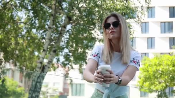 блондинка пьет кофе на улице - Кадры, видео
