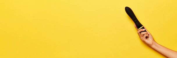Banner. Mano femenina con vibrador, masajeador médico sobre fondo amarillo. Imagen para sex shop. Concepto de salud, medicina. Copyspace para anuncio, texto - Foto, Imagen