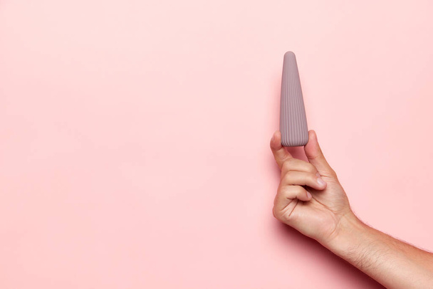 Mannetjes hand met vibrator, medische massager over pastel roze achtergrond. Afbeelding voor seksshop. Concept van gezondheid, geneeskunde. Copyspace voor reclame, tekst - Foto, afbeelding
