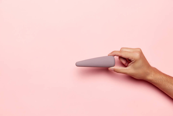 Γυναικείο χέρι με δονητή, ιατρική συσκευή μασάζ πάνω από παστέλ ροζ φόντο. Εικόνα για σεξ σοπ. Έννοια της υγείας, της ιατρικής. Copyspace για διαφήμιση, κείμενο - Φωτογραφία, εικόνα