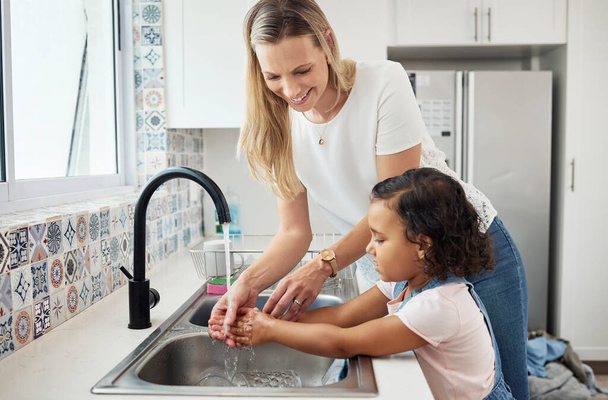 Mère, enfant et se laver les mains à l'évier de la cuisine à la maison pour une bonne hygiène, santé et bien-être. Une femme, un enfant ou une fille apprenant les soins de la peau, le nettoyage et la sécurité contre les germes ou la saleté à la maison familiale. - Photo, image
