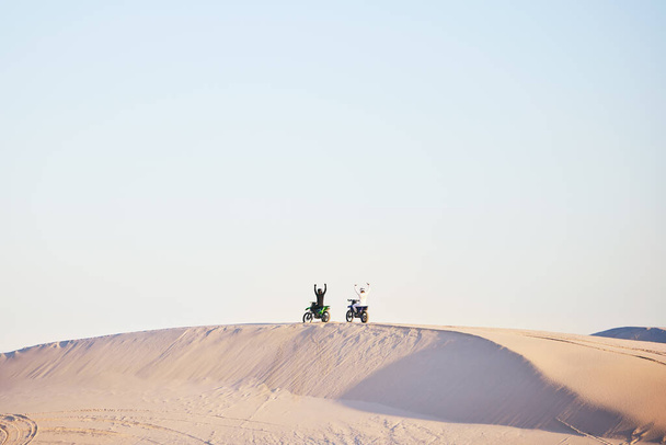 Motorbike, race celebration and desert on sand, competition or outdoor hill for sky background, goal or off road. Motorcycle athlete, ramp and nature with win, success and contest with mockup space. - Фото, изображение