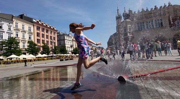 Yuoth seeking escape from the summer heat in Main Square in Cracow, Poland - Foto, imagen