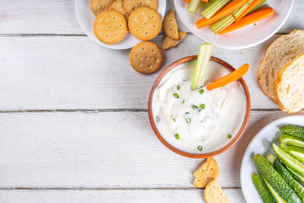 Cottage cheese high-protein dip with fresh vegetables, bread and crackers on wooden white table copy space. Eating diet healthy curd cheese spread with various snacks - Photo, Image