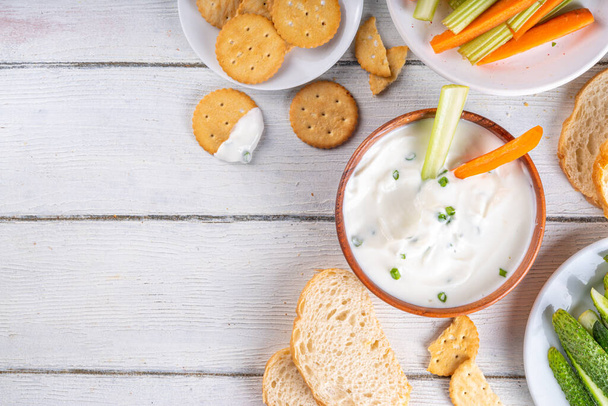 Cottage cheese high-protein dip with fresh vegetables, bread and crackers on wooden white table copy space. Eating diet healthy curd cheese spread with various snacks - Photo, Image