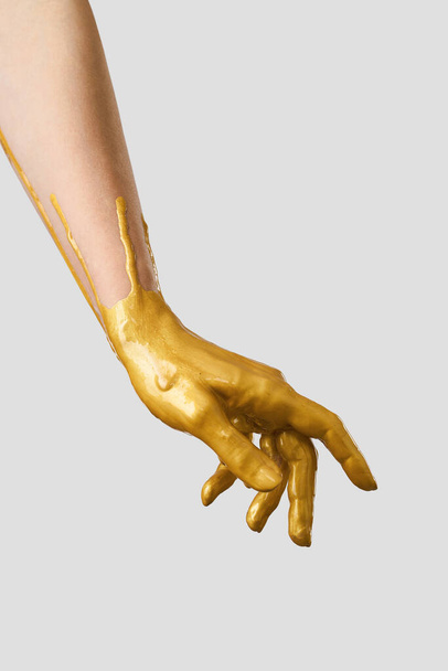 The hand is in gold acrylic paint, the paint covers the hand like a latex glove. - Fotoğraf, Görsel