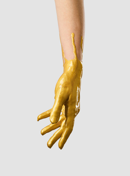 The hand is in gold acrylic paint, the paint covers the hand like a latex glove. - Foto, Imagen