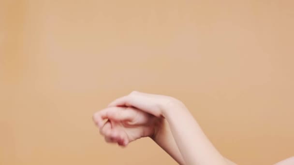 Woman applies cream on hands against orange background closeup. Skincare cosmetic products - Footage, Video