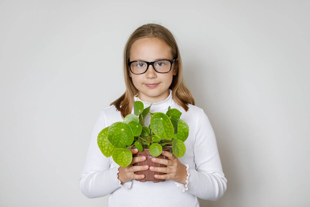 Okos kislány kezében zöld növény pot fehér háttér. Hobbi, szabadidő, kertészkedés és környezetvédelem és a Föld Napja koncepció - Fotó, kép