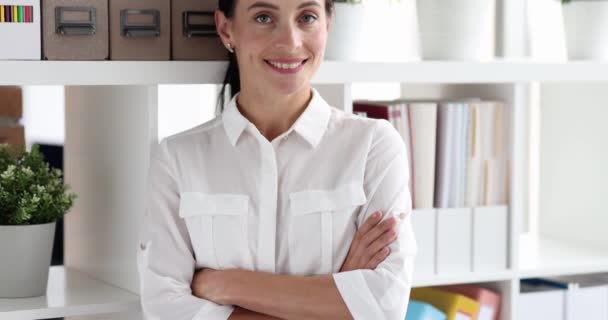 Young woman standing near shelving with folders of documents and smiling 4k movie. Medium business development concept - Footage, Video
