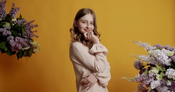 Kis vicces szőke gyerek tini tizenéves lány 12 év bézs ruhában ő boldog és mosolyog a sárga háttér a stúdióban. Gyönyörű boldog tini lány mosolyog. - Felvétel, videó